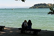 People sitting on a bench and looking at the lake
